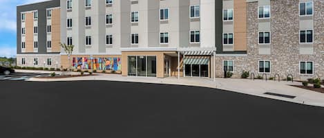 A modern hotel with a flat roof, multiple floors, and a large entrance area.