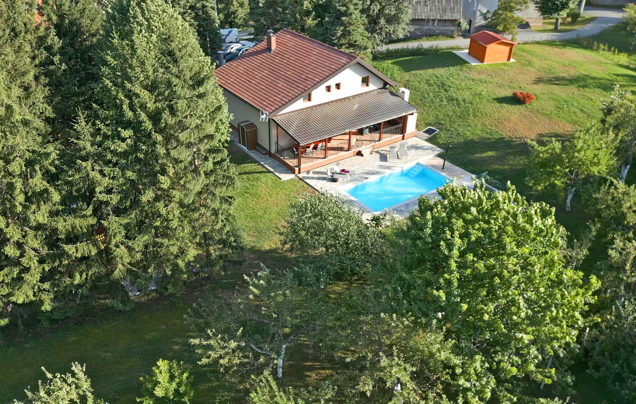 Ett hus med en swimmingpool, omgivet av täta träd.