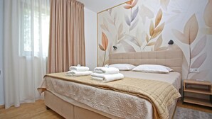 A neatly made bed with a beige headboard and a floral wall mural. - Nice home in Ogulin with sauna (Ogulin)