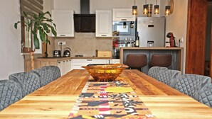 A dining table with a colorful runner, two cushioned chairs, and a modern kitchen in the background. - Nice home in Ogulin with sauna (Ogulin)