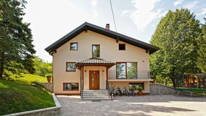 A two-story house with a balcony, a stone wall, and a paved driveway. - Nice home in Ogulin with sauna (Ogulin)