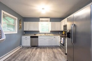 A kitchen with white cabinets, a stainless steel refrigerator, and a dishwasher.