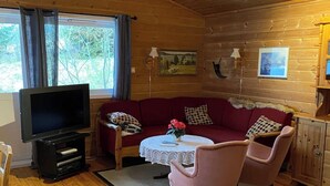A cozy cabin interior with a wooden ceiling, a sofa set, a television, and a dining table. - Amazing place with boat, kayak, SUP and mountain view. Wifi and free parking.  (Nordland)