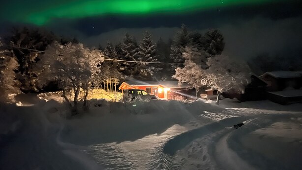 A snow-covered landscape with a lit cabin and a clear view of the northern lights. - Amazing place with boat, kayak, SUP and mountain view. Wifi and free parking.  (Nordland)