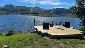 A wooden dock with a bench and speakers, overlooking a calm lake with mountains in the background. - Amazing place with boat, kayak, SUP and mountain view. Wifi and free parking.  (Nordland)