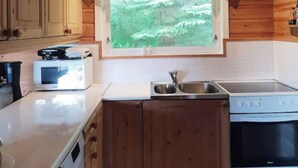 A compact kitchen with wooden cabinets, a microwave, a sink, and a stove. - Amazing place with boat, kayak, SUP and mountain view. Wifi and free parking.  (Nordland)