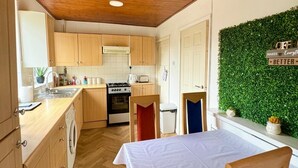 Une cuisine compacte avec des meubles en bois, une cuisinière et un évier. On y trouve également un coin repas avec une table et des chaises.