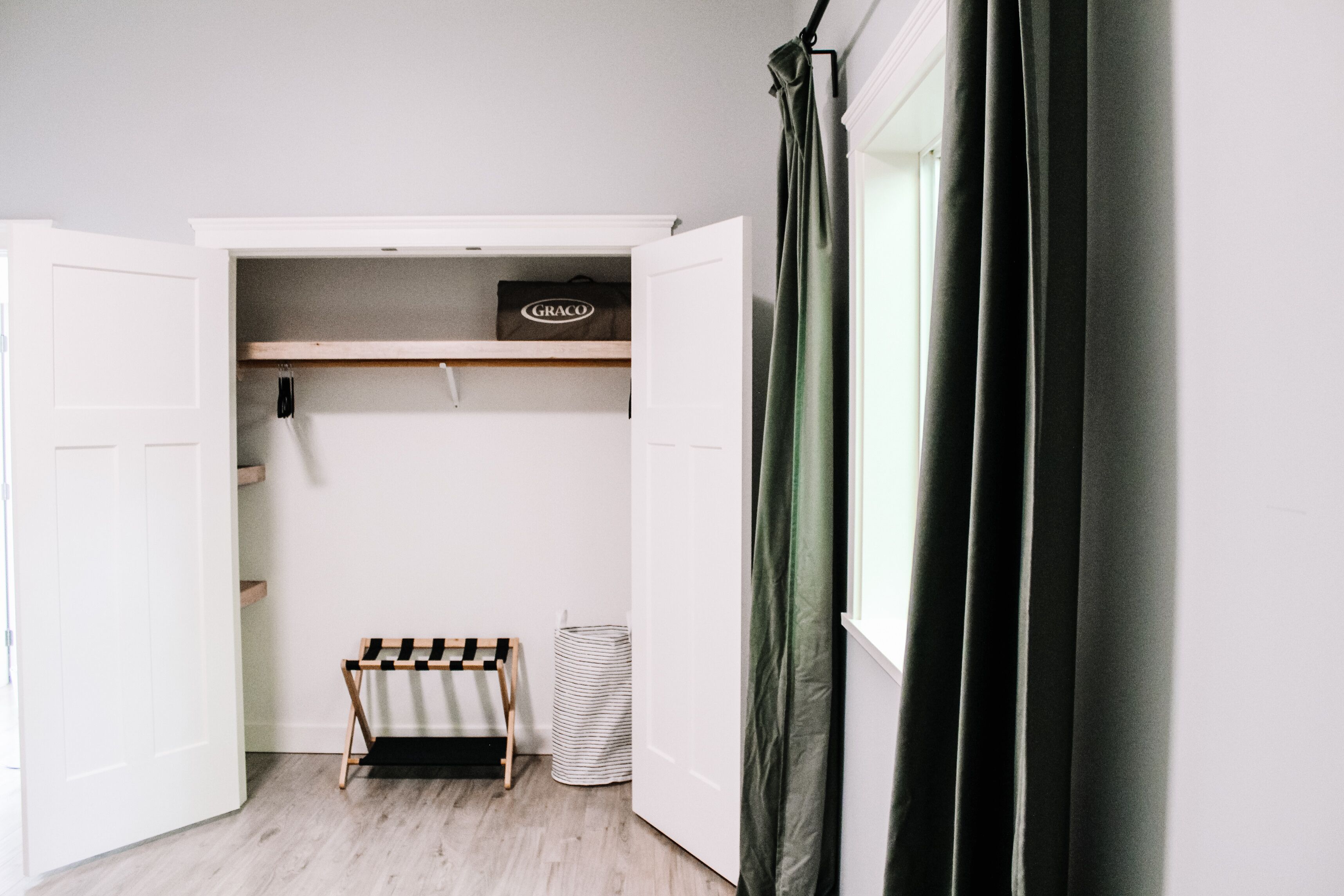 Un dressing avec une tringle à vêtements, une boîte de rangement et un panier à rayures.