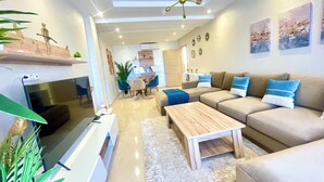 Una sala de estar moderna con un sofá, una mesa de centro, televisor y elementos decorativos.
