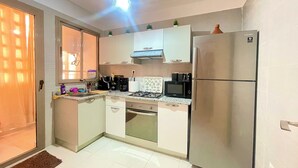 Una cocina compacta equipada con refrigerador, microondas, estufa y pileta.