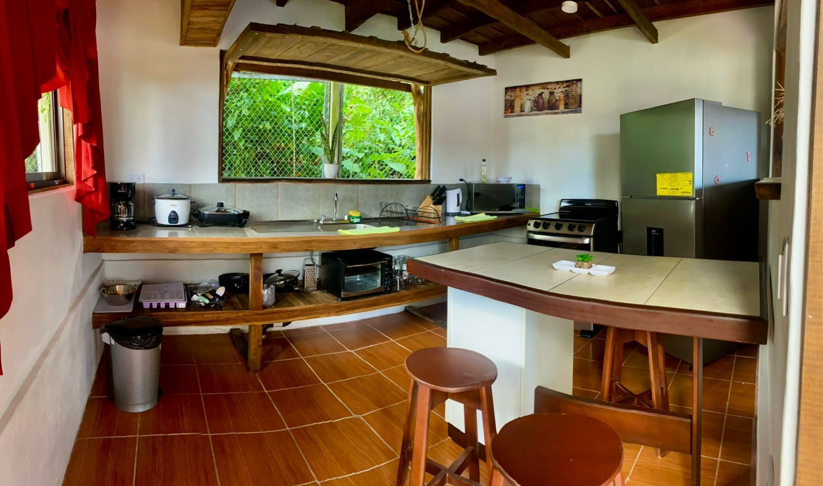 A compact kitchen with a wooden countertop, a microwave, a stove, and a refrigerator.
