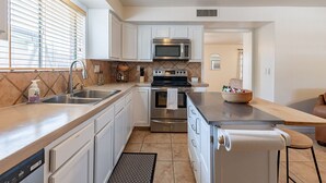 A kitchen with white cabinets, stainless steel appliances, a sink, and a countertop. - Charming 4-bedroom house, family and pet friendly, in desirable east Tucson! (Tucson)