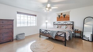A bedroom with a bed, dresser, window, ceiling fan, and a mirror. - Charming 4-bedroom house, family and pet friendly, in desirable east Tucson! (Tucson)