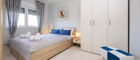 A modern bedroom with a wooden bed, a bedside table with a lamp, a bench, and a wardrobe.