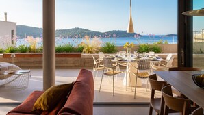 Un espace de restauration extérieur moderne offrant une vue sur la mer et les collines.