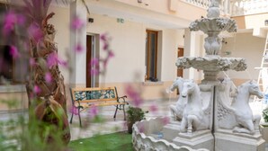 A fountain with horse statues, a bench, and a door in a courtyard. - hotel du parc canal (Saint-Denis)