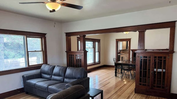 A spacious living room with a leather sofa, wooden flooring, and large windows.