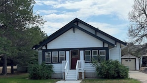 A single-story building with a gabled roof, a front door, and a small set of stairs leading to the entrance.