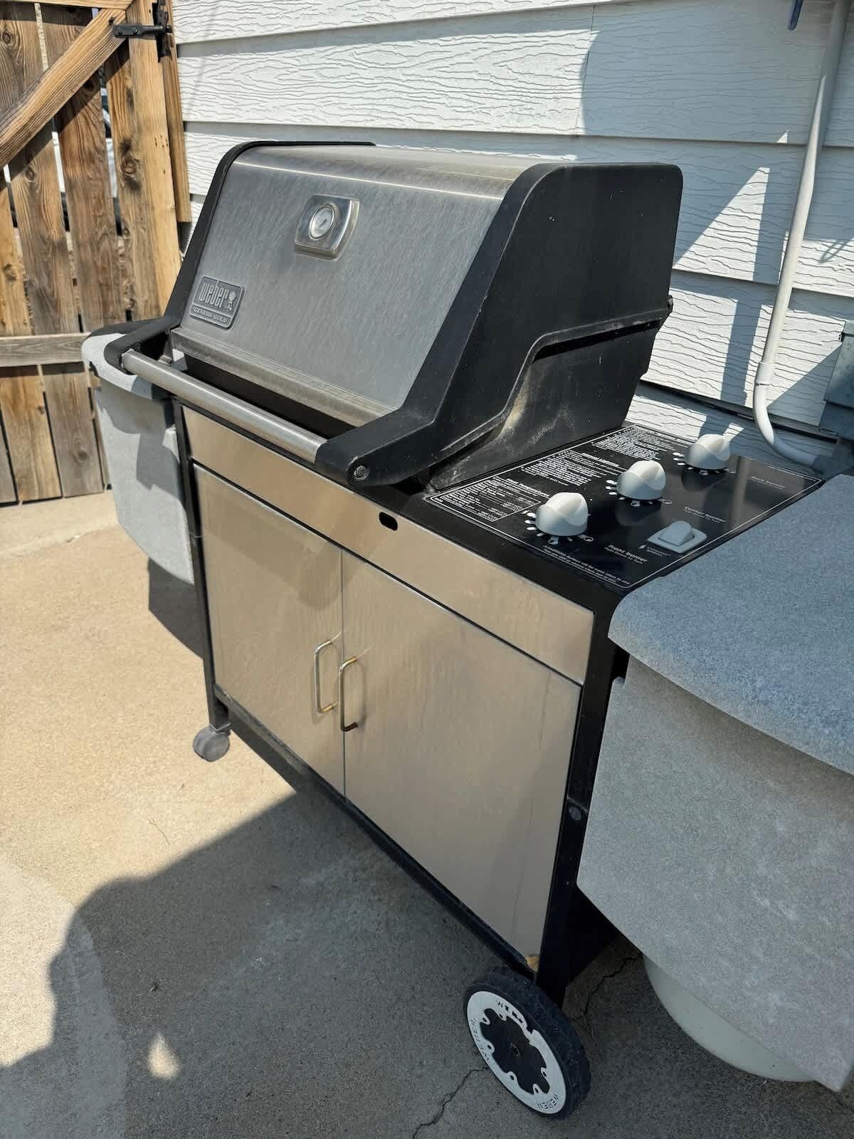En transportabel grill med kontrolpanel, hjul og et opbevaringsskab.