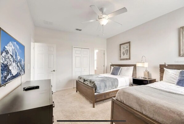 A hotel room with a bed, bedside tables, a ceiling fan, a TV, and a painting on the wall.