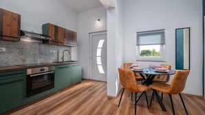 A modern kitchen with green cabinets, a wooden countertop, and a dining area with a table and chairs. - Beautiful apartment in Galizana (Galizana)