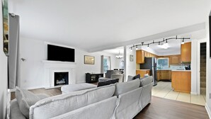 Una sala de estar moderna con un sofá, una chimenea y una cocina con armarios de madera y encimera.