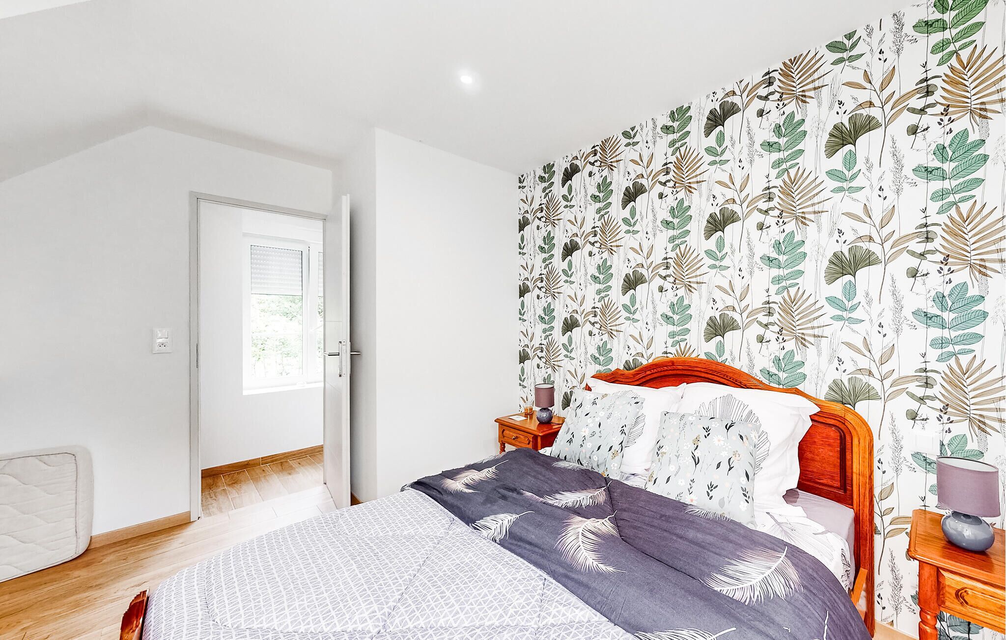 A bedroom with a bed, a nightstand, a lamp, and a window with blinds.