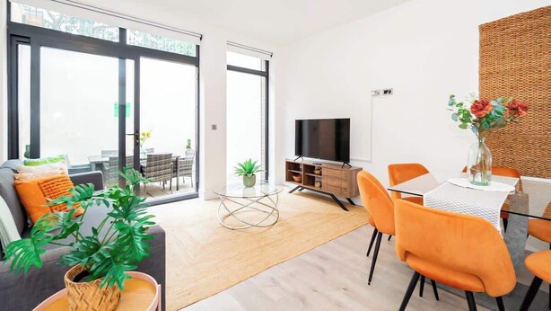 Una sala moderna con sofá, televisor, mesa de comedor y sillas.