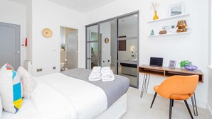 Una habitación de hotel moderna con una cama, un escritorio y una silla. Hay una puerta corredera que da a un baño.