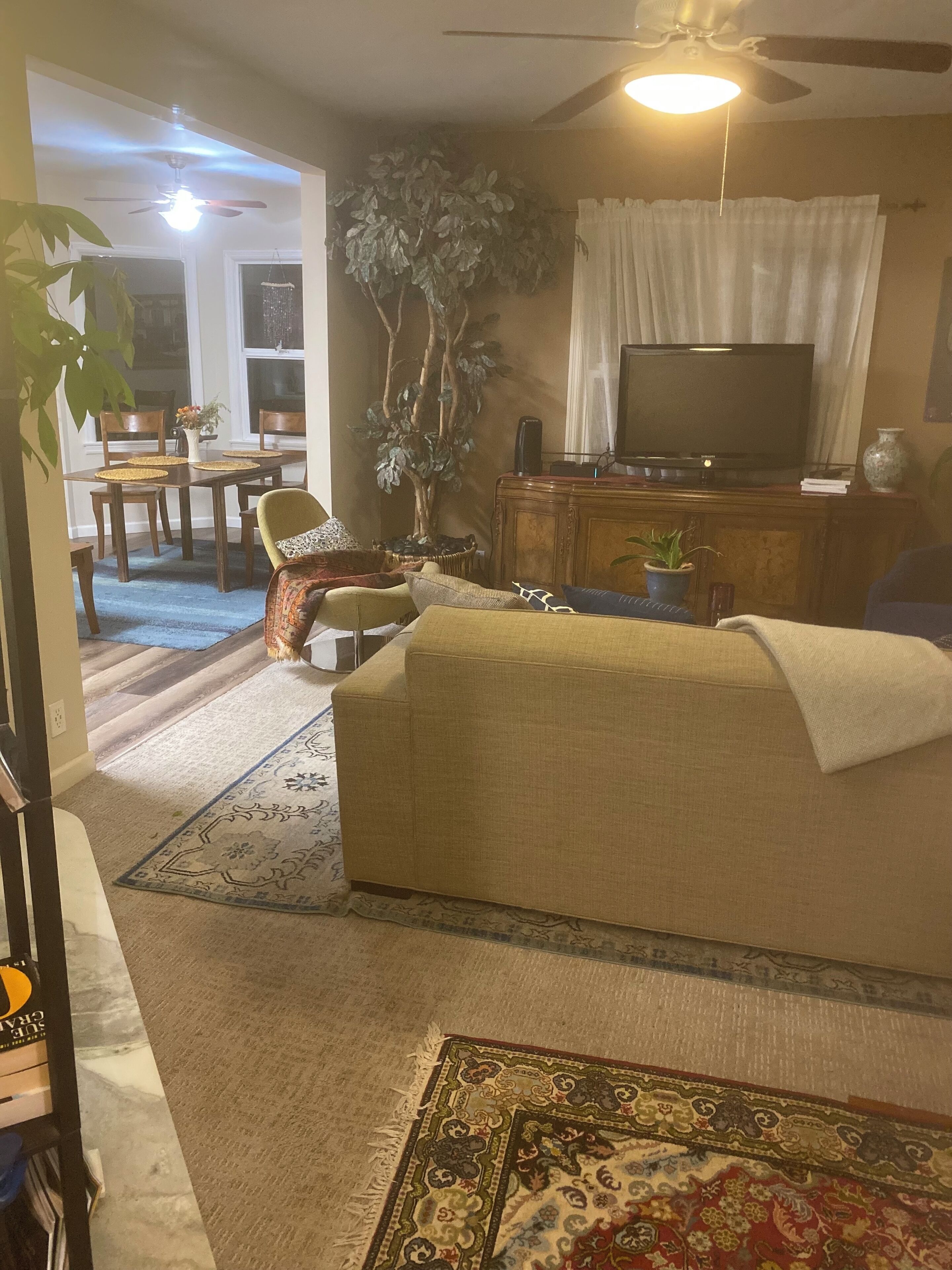 Una sala de estar con sofá, televisión, mesa de comedor y sillas.