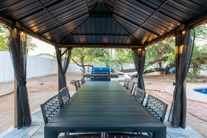 Un espace extérieur abrité, aménagé avec un barbecue et des chaises.