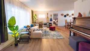 Una sala de estar con un piano, un sofá, una mesa de centro y un comedor con sillas.