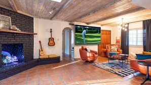 Una sala de estar acogedora con chimenea, un televisor mostrando un partido de golf y asientos cómodos.
