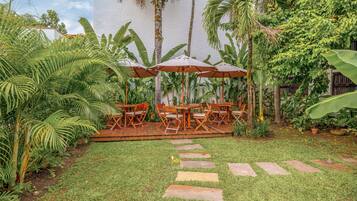 A patio with outdoor furniture, stone steps, and lush greenery.
