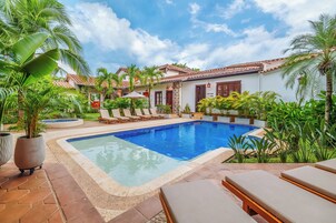 Una piscina al aire libre, sombrillas, sillones reclinables de piscina