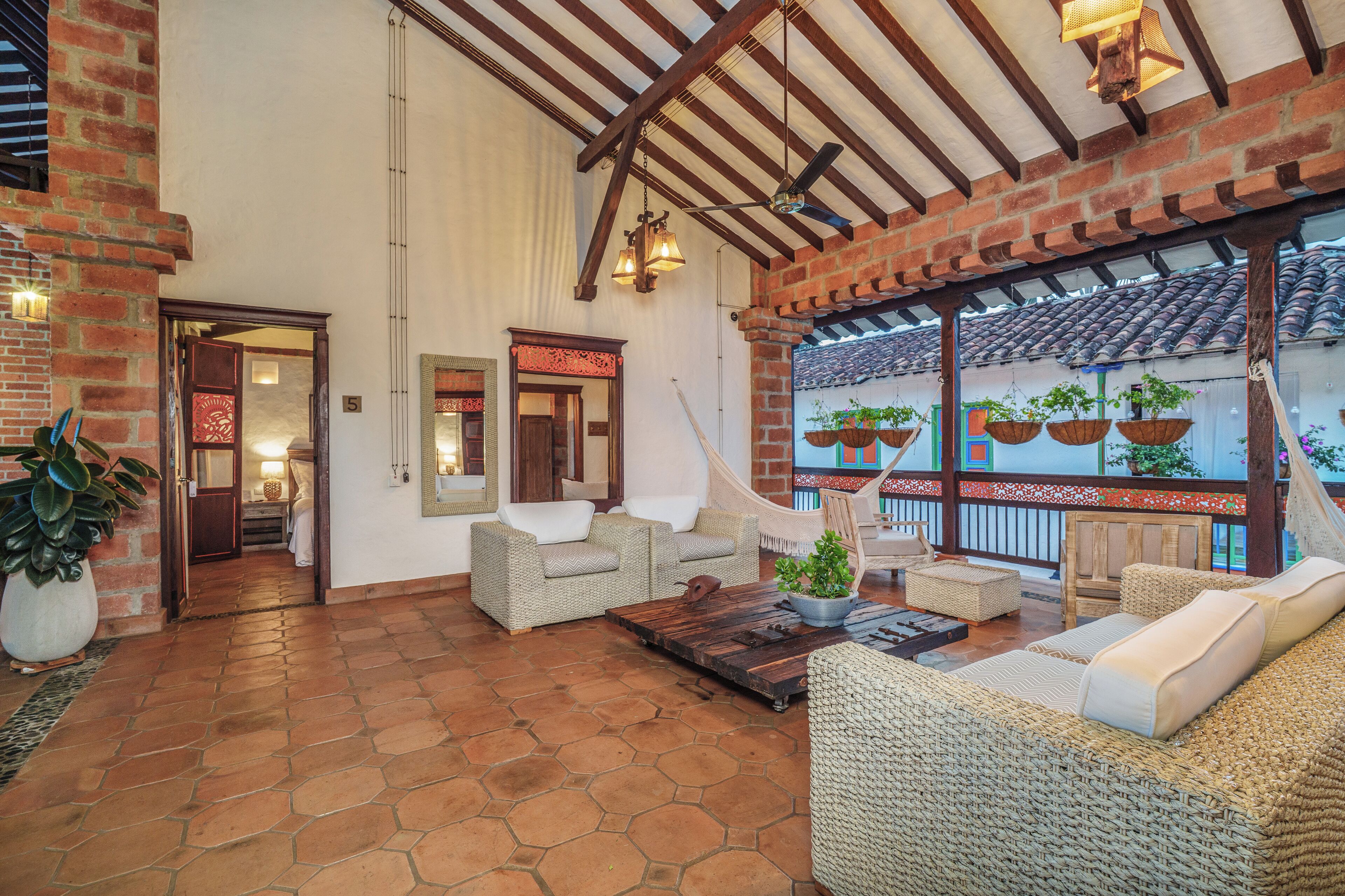 A spacious indoor area with wicker furniture, a large potted plant, and a ceiling fan.