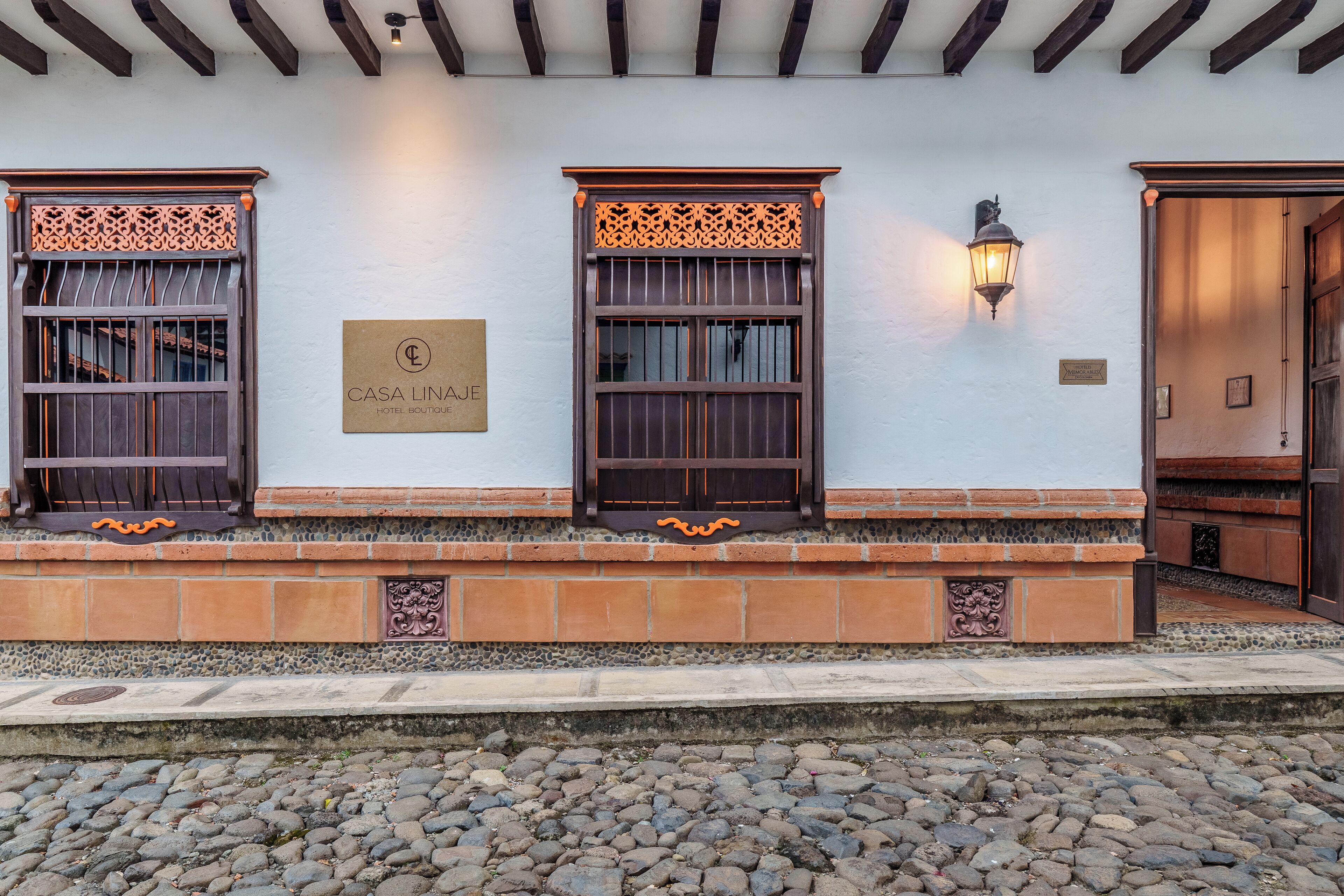 A building facade with a sign reading "CASA LINACE HOTEL BOUTIQUE," featuring decorative window grills and a stone base.