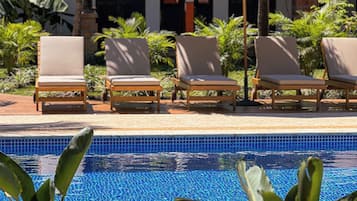 Una piscina al aire libre, sombrillas, sillones reclinables de piscina