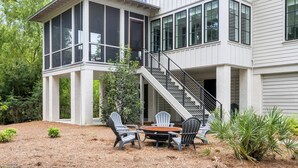 A two-story house with a large bay window, a covered patio with outdoor furniture, and a staircase leading to the upper floor. - Tucked among the treetops and steps to walking trail (Bluffton)