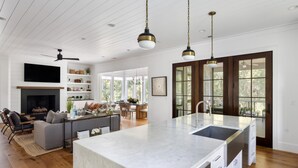 A spacious living area with a large island, wooden floors, and a fireplace. - Tucked among the treetops and steps to walking trail (Bluffton)