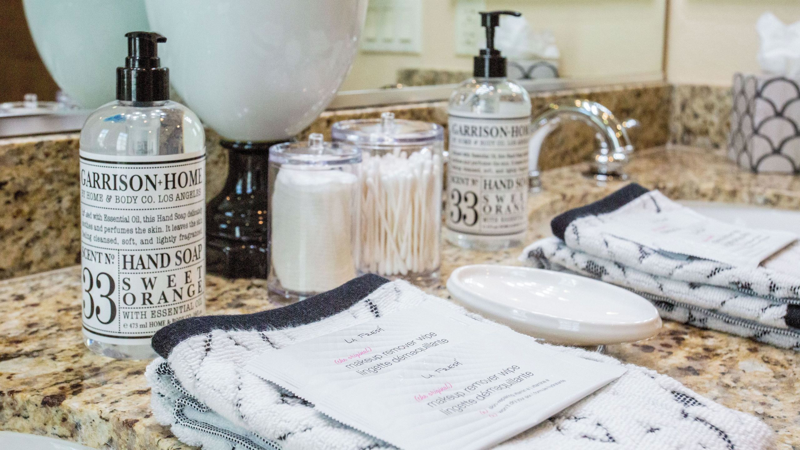 A bathroom counter with hand soap, cotton swabs, and a hand soap pump dispenser.