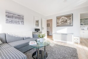Ein modernes Wohnzimmer mit einem gestreiften Sofa, einem Glastisch und einer Heizung.