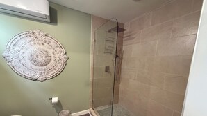 Un baño con ducha acristalada, inodoro y un adorno en la pared.