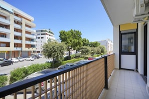 A balcony with a view of a street, parked cars, and buildings.