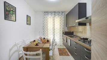 Une cuisine compacte comprenant une table à manger, des chaises et un petit comptoir.