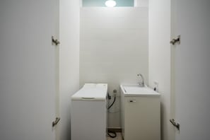 A small, white bathroom with a washing machine and a sink.
