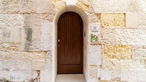 A stone building with a wooden door and a small sign above it.