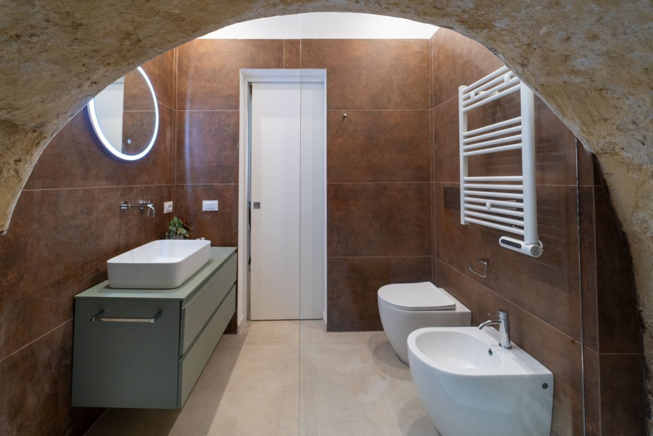 A bathroom with a sink, toilet, and mirror.