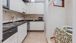 Een kleine keuken met witte kastjes, een zwart aanrecht, een spoelbak en een magnetron.