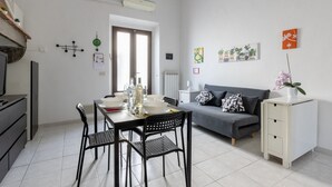 A modern living space with a dining area, a sofa, and a small cabinet. - GuestHost - Spacious 50 sqm apartment, ideal for 4 people, located on the ground floor of a building WITHOUT lift (NOT suitable for disabled people). The apartment is located a 9-minute walk from Pisa-Galileo Galilei airport and 6 minutes by public trans (Pisa)